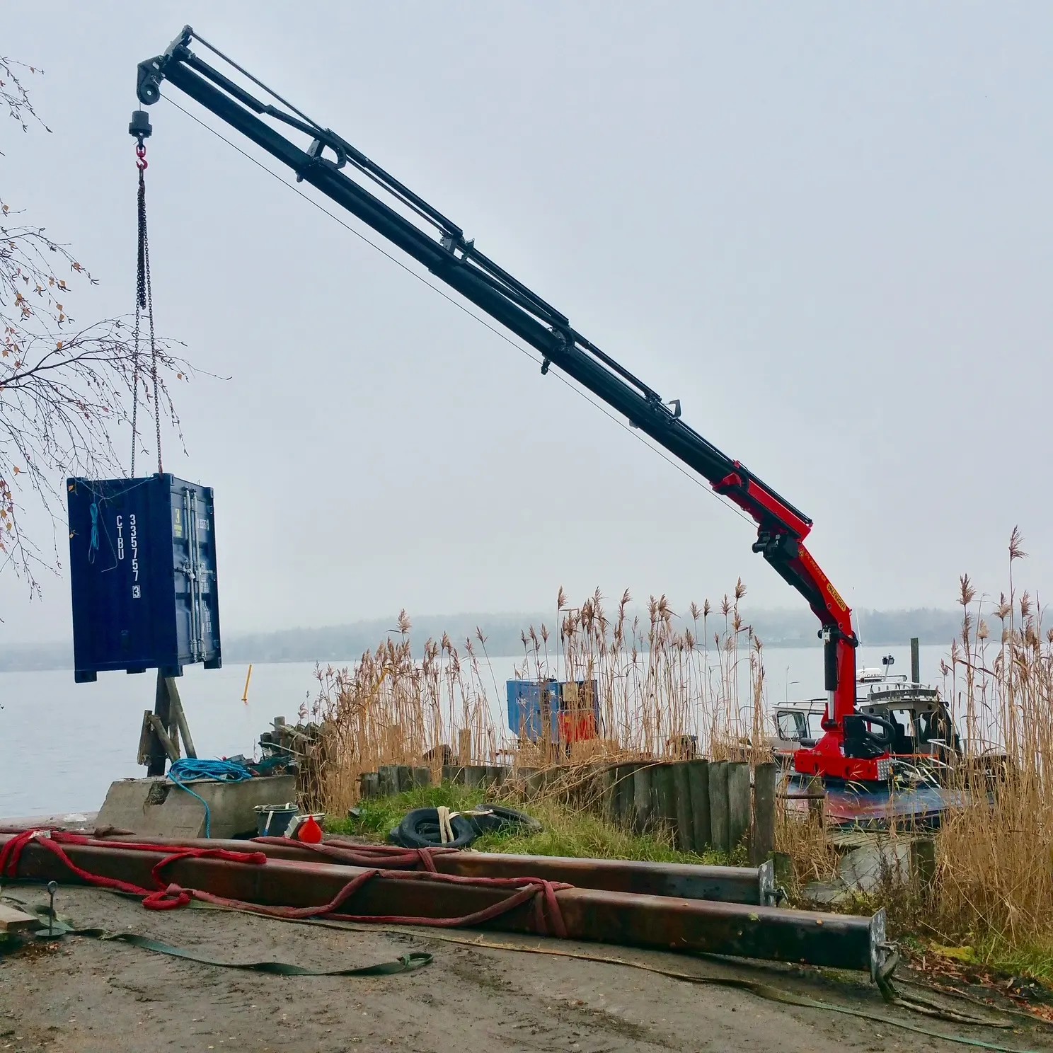 Hydraulisk kran lyfter en container vid vattnet