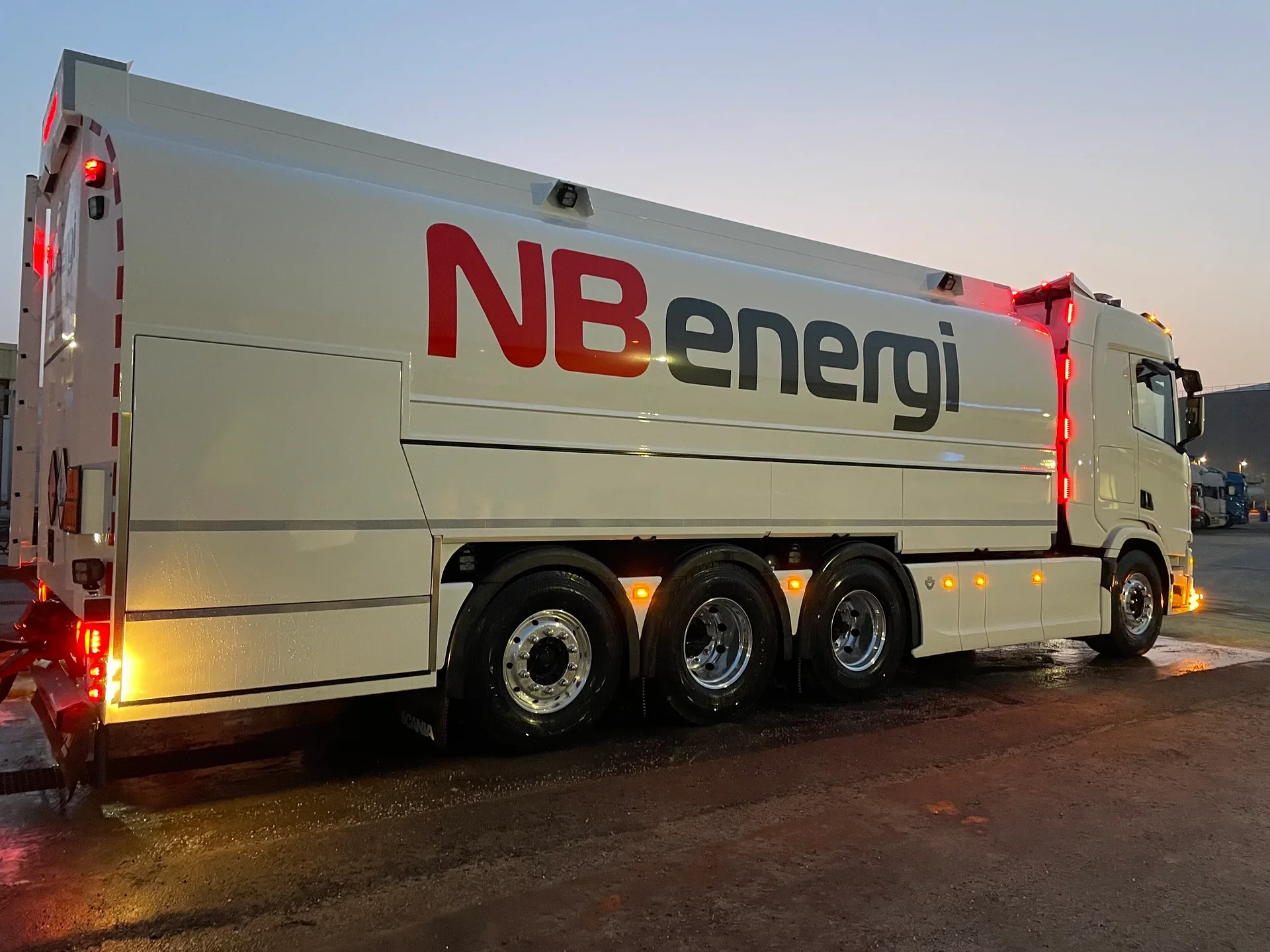 Vit tankbil med NB Energi-dekor i skymningen