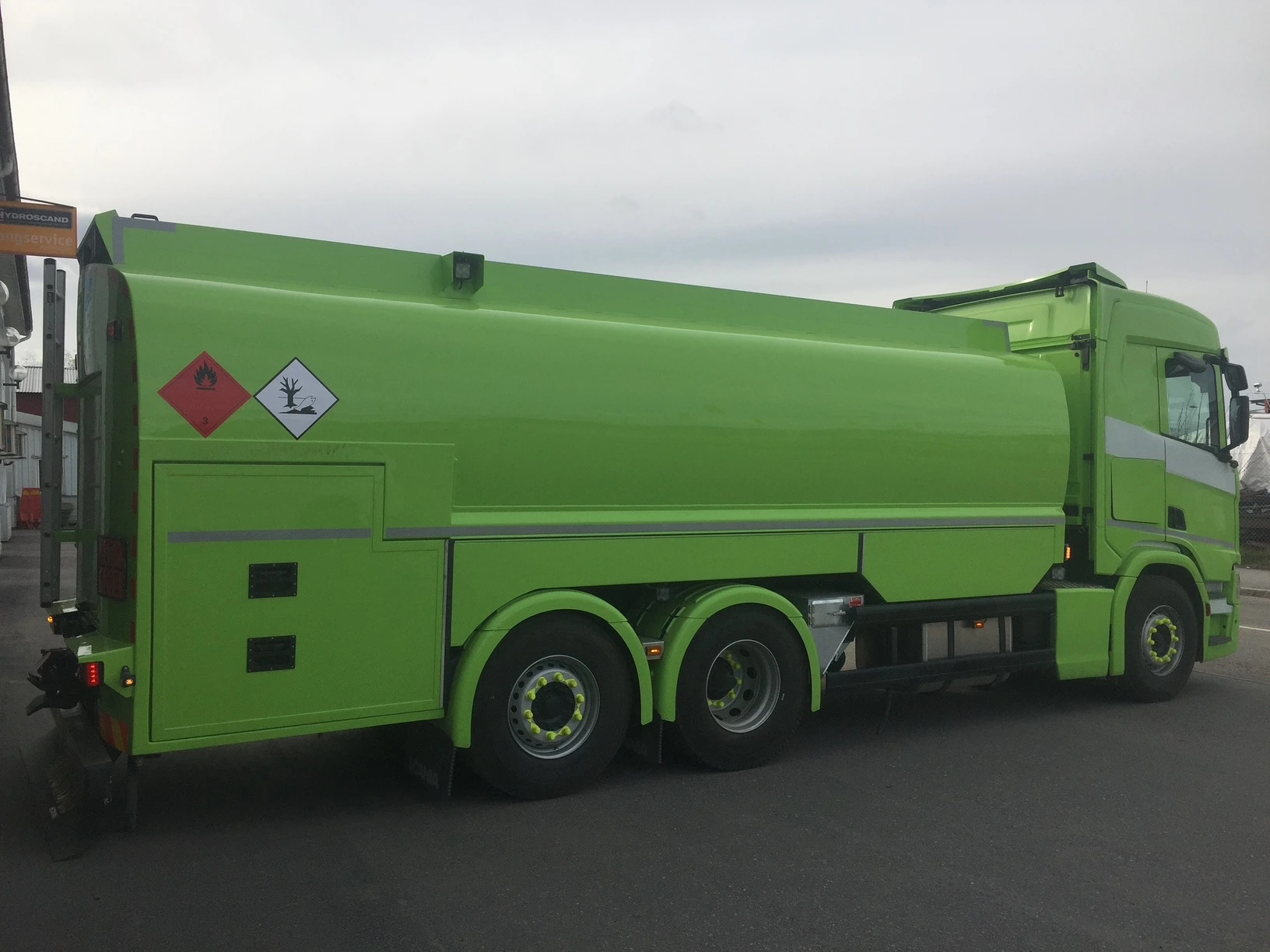 Grön tankbil med varningsskyltar parkerad utomhus