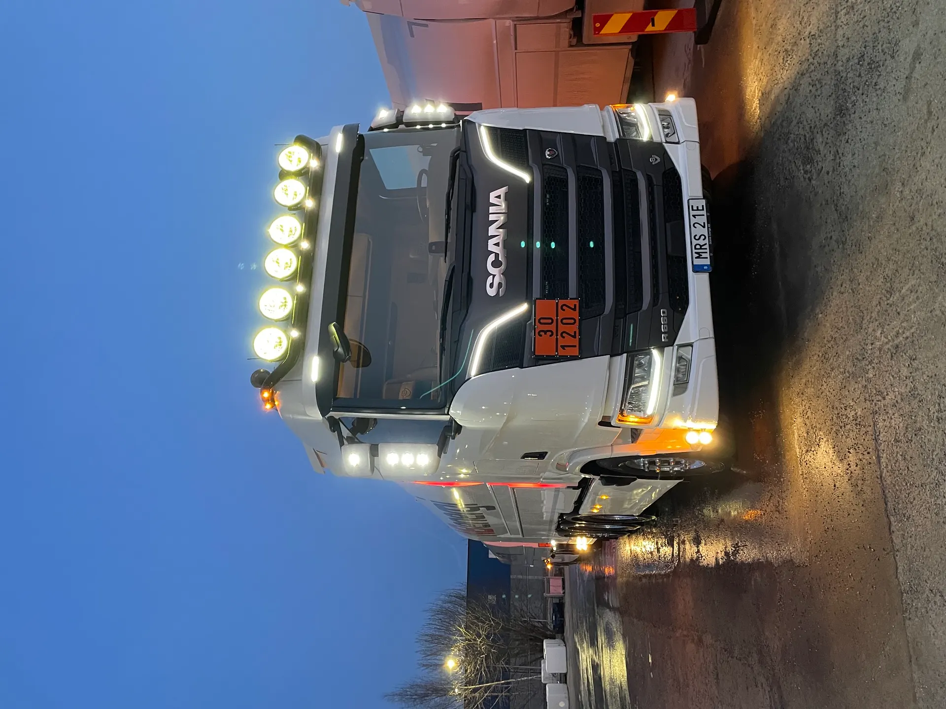 Vit Scania-tankbil med extraljus i kvällsljus